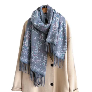 Écharpe en cachemire bleu à motif paisley et franges drapée sur un manteau