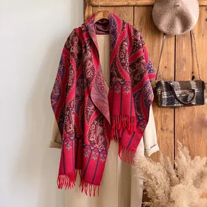 Detail of bohemian red paisley cashmere shawl with elegant fringe tassels for winter