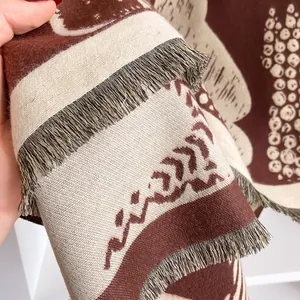 Close-up of jacquard knit scarf showing brown wave patterns and delicate fringe detail