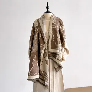 Detail of knitted cat pattern and fringe edges on a warm brown and beige autumn shawl