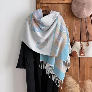 Close-up of vintage paisley pattern embroidery and white tassels on a warm winter shawl