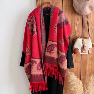 Vintage red paisley cashmere-like shawl with tassels on a wooden hanger for autumn and winter