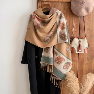 Detail of vintage paisley pattern and tassels on khaki cashmere-feel winter shawl