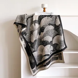 Dettaglio dello scialle pashmina con motivo a foglie di ginkgo e frange sul rack