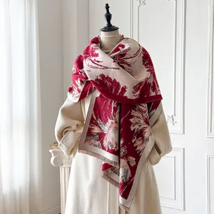 Dettaglio di sciarpa floreale rossa e beige con frange su un cappotto beige