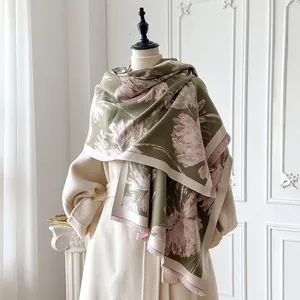 Dettaglio di sciarpa floreale verde oliva con frange su un cappotto beige autunnale