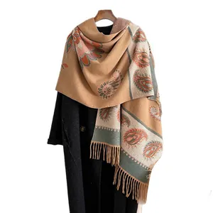 Vintage paisley floral scarf with long tassels draped over a coat on a hanger