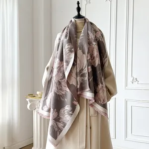 Dettaglio di sciarpa invernale floreale con nappe su un cappotto beige in stanza classica