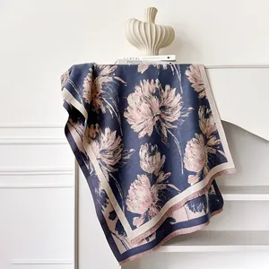 Dettaglio di sciarpa floreale blu navy con fiori rosa e bordo con frange