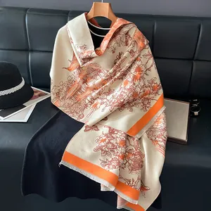 Detail of cream cashmere-feel scarf with orange trim and classic Chinese landscape print