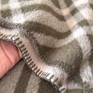 Dettaglio della trama cashmere a quadri verdi e beige con bordo rifinito a mano di lusso