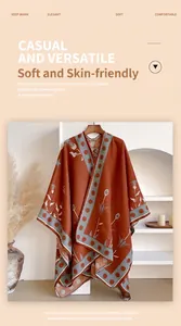 Detail van een vintage roodbruine gebreide cape sjaal met witte bloemmotieven en bies