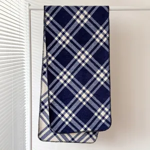 Dettaglio macro della sciarpa a quadri blu navy con bordi cuciti a punto nero