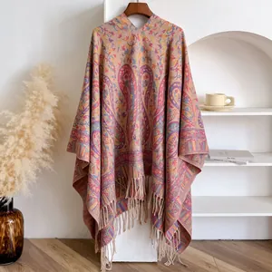 Detail of bohemian paisley knit shawl featuring decorative fringes on a wooden hanger