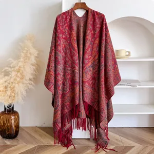 Detailed view of red paisley knit shawl with tassel fringe on a wooden hanger