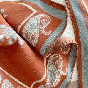 Detailed macro view of bohemian paisley patterns and overlock stitching on warm cashmere shawl