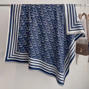 Nahaufnahme der marineblauen und weißen Jacquard-Buchstaben auf warmem Schal mit Fransen