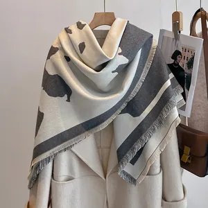 Detail eines grau-beigen Jacquard-Schals mit dicken Fransen und weicher Textur
