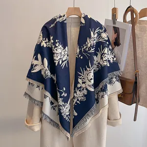 Detailansicht des geblümten Schals in Marineblau und Weiß auf einem beigen Wollmantel