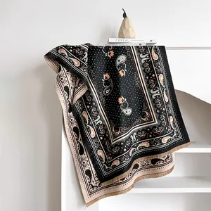 Detail eines Kaschmirschals mit Paisley-Muster und Fransen im Bücherregal