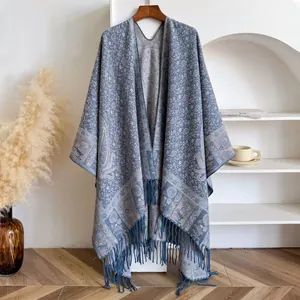 Detail of blue paisley floral shawl with long fringe tassels on a wooden hanger