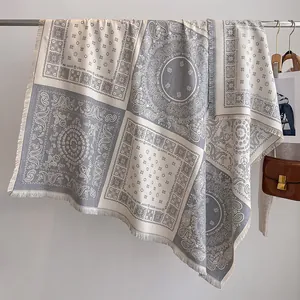 Détails de motifs paisley gris et beige avec fines franges sur un châle doux au toucher