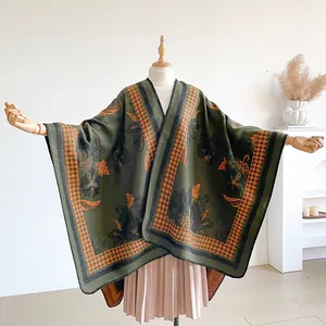 Detail of dark green floral shawl with orange houndstooth trim on a mannequin