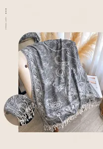 Gros plan d'une écharpe jacquard à motif paisley gris avec des franges décoratives