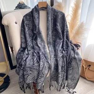 Macro detail of charcoal paisley jacquard scarf fabric with elegant fringe tassels