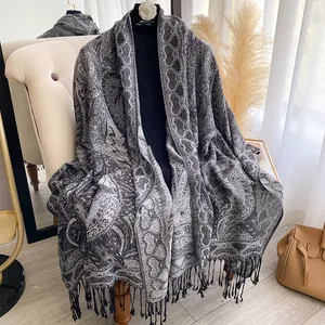 Gros plan sur un châle jacquard cachemire gris et noir avec des finitions à franges