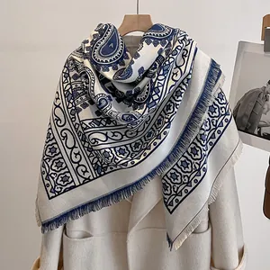 Detail eines Paisley-Kaschmirschals in Marineblau und Beige mit Fransen auf Mantel
