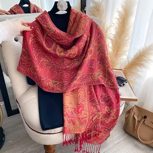 Detail of red and gold paisley jacquard scarf with decorative fringe tassels on a chair
