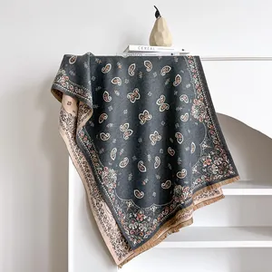 Thick paisley print scarf with fringe edges draped elegantly over a minimal white shelf