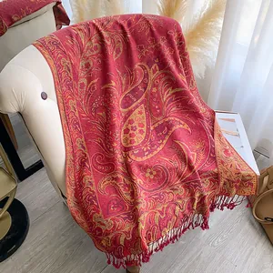 Close-up of ethnic paisley jacquard pattern with fringe details on a red long shawl