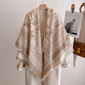 Detail eines luxuriösen Paisley-Jacquard-Schals mit Fransen auf einem weißen Mantel
