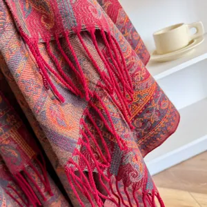 Primer plano de bufanda de cachemira con patrón paisley rojo y flecos anudados