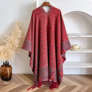 Close-up of red floral jacquard knit poncho with fringe details and V-neckline