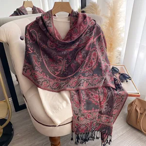Dettaglio scialle paisley morbido con nappe drappeggiato su poltrona stile autunnale