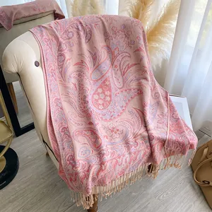 Close-up of pink paisley floral jacquard scarf with decorative fringe on a white sofa
