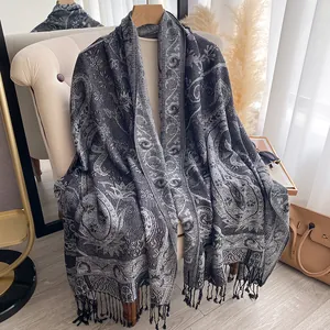 Dettaglio di sciarpa jacquard con motivo paisley e nappe nere su grucce di alta qualità