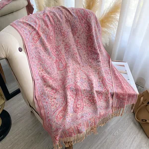 Detail van paisley sjaal met franjes op een comfortabele witte fauteuil in huis