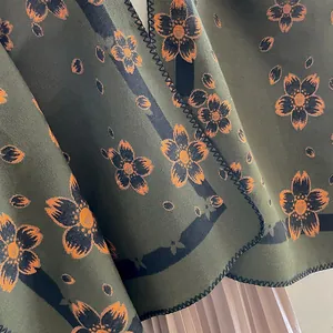 Deep green cashmere feel poncho with orange floral patterns and black stitched edges