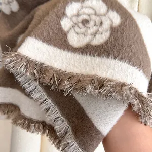 Close-up of the woven camellia flower pattern and soft fringe on the striped scarf
