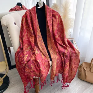 Détail d'un châle cachemire rouge et or à motif paisley avec des franges élégantes