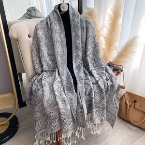 Detail of grey paisley jacquard scarf with long white tassels on an elegant chair