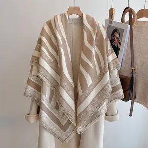 Gros plan du poncho tricoté avec motif zèbre, détails de franges et capuche