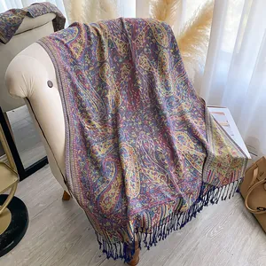 Detailopname van paisley sjaal met lange franjes gedrapeerd op een beige bank