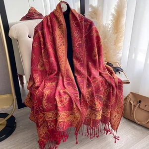 Dettaglio sciarpa rossa in cashmere con motivi paisley dorati e nappe con frange