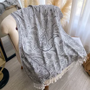Detailed view of gray paisley jacquard fabric featuring delicate white handmade fringe
