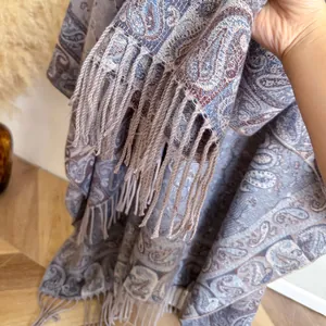 Detail van blauwe en beige paisley jacquard sjaal met kwastjes voor herfst en winter